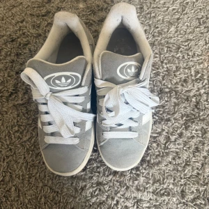 Grå Adidas Campus sneakers - Säljer ett par grå Adidas Campus sneakers med vita detaljer och snörning. I väldigt bra skick och knappt använda🤍