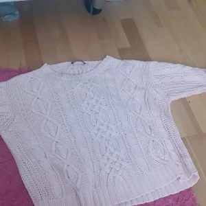 Rosa stickad tröja - Säljer en söt rosa stickad tröja med flätmönster. Tröjan har en rund hals och långa ärmar, perfekt för kyligare dagar. Den är både mysig och stilren, ett måste i garderoben! 💖