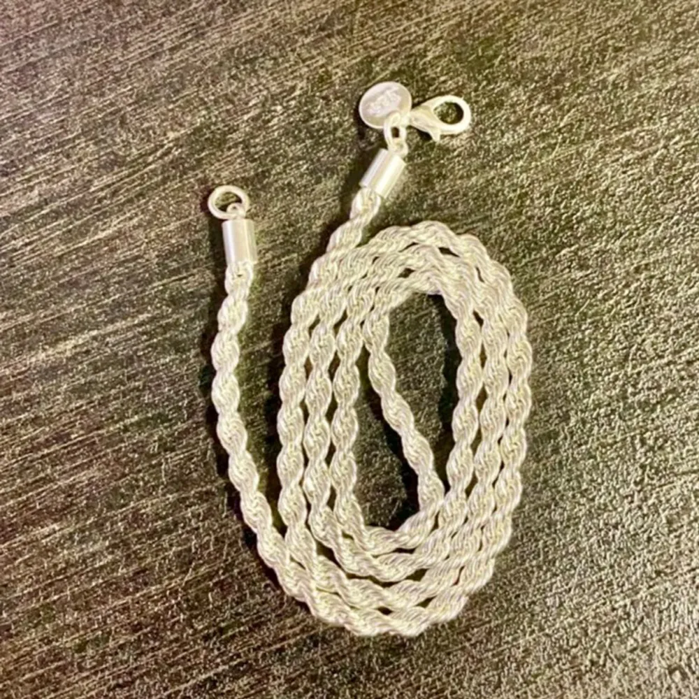 Snyggt silverfärgat pläterade halsband med en tvinnad design. Halsbandet är märkt med 925, vilket indikerar att det är tillverkat av sterlingsilver. Perfekt för att ge en elegant touch till din stil.l nyskick • längd 51cm • bredd 5mm • 24 gr. Asusteet.