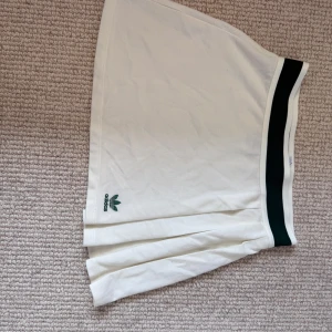Tenniskjol - En krämvit tenniskjol från adidas, med gröna detaljer. Knappt använd🩷