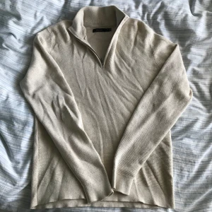 Beige stickad tröja från Matinique - Säljer en stilren beige stickad tröja från Matinique med dragkedja vid halsen. Tröjan har långa ärmar och en mjuk, bekväm passform. Perfekt för kyligare dagar.