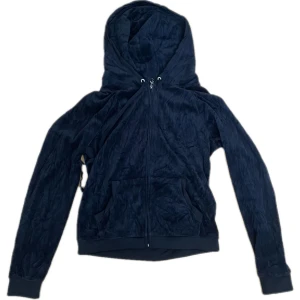 Svart hoodie från Juicy Couture - Säljer en snygg svart hoodie från Juicy Couture med dragkedja och huva. Baksidan har ett stort Juicy Couture-tryck i silver.