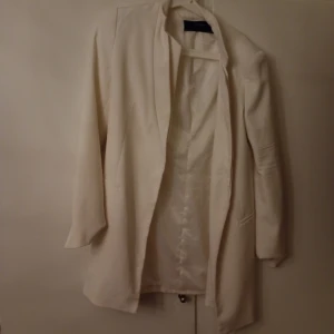 Vit kavaj från Zara Basic Collection - Elegant vit kavaj från Zara Basic Collection. Den har en stilren design med långa ärmar och en klassisk passform. Perfekt för att ge en sofistikerad touch till din outfit.