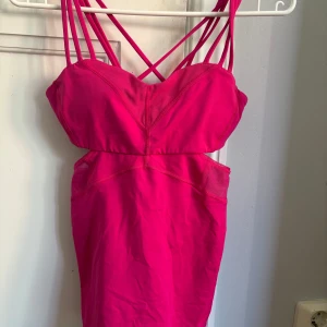 Rosa linne från Lululemon - Snygg rosa träningslinne från Lululemon med flera smala axelband och en tight passform i storlek 4. Perfekt för en sportig och stilren look. Materialet är en blandning av nylon och lycra för extra komfort och stretch.