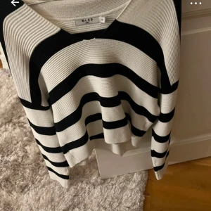 Randig tröja från NA-KD - Säljer en snygg randig tröja från NA-KD i svart och vit. Tröjan har en lös passform med långa ärmar och en v-ringad hals. Perfekt för en stilren look.