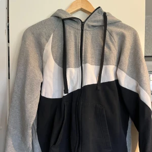 nike zip up hoodie - grå, vit och svart zip up hoodie med nike tryck. använd ett fåtal gånger men bra skick. tjock, perfekt till träning eller vardag. snörena och insidan är liite noppriga men märks knappt. längd från axeln- 66 cm, bredd - 50 cm