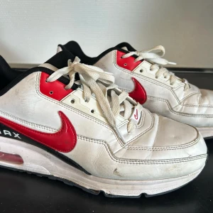 Nike Air Max Ltd 3 vita och röda sneakers - Snygga Nike Air Max sneakers i vitt med röda och svarta detaljer. Skorna har en klassisk design med snörning och den ikoniska Nike-loggan på sidan. Perfekta för en sportig look.