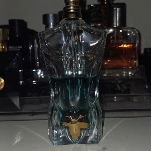 Jean paul gaultier le beau edt. Tar byten - Unik parfymflaska formad som en manlig torso med en blå vätska inuti. Flaskan har en elegant design med detaljer i guld vid basen. Perfekt för den som vill ha en iögonfallande och stilren parfymflaska i sin samling.