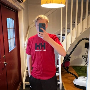 Röd t-shirt från Helly Hansen - Säljer en röd t-shirt från Helly Hansen med deras ikoniska logga i svart och vitt på bröstet. Storlek M/L