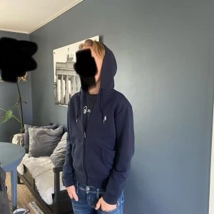 Mörkblå hoodie från Polo Ralph Lauren (INTRESSEKOLL) - Säljer en riktigt snygg zip hoodie från raffe, skriv om ni är intresserade, ny pris runt 1500kr mitt pris 1299, skick: 9/10 , mycket bra skick som sagt men ändå använd, inga hål eller defekter av något slag. Storlek XS, modellen är 168cm och  väger 55kg