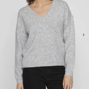 Grå stickad tröja  - Säljer en stilren grå stickad tröja från Vila med v-ringning. Tröjan har långa ärmar och en mjuk, bekväm passform. Tröjan är aldrig använd så den är i nyskick! Hör av er vid frågor 😊