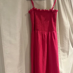 Rosa klänning med smockdetaljer - Säljer en söt rosa klänning med smockdetaljer upptill och smala justerbara  axelband. Aldrig använd!🩷 