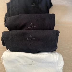 Svarta och vit-shirts från GANT - Säljer ett set av 3 svarta och en vit-shirts från GANT. Perfekta för en stilren och enkel look. T-shirtsen har en normal passform och är tillverkade i mjukt material för extra komfort. Logotypen är diskret placerad på bröstet. Strl M. Rök och djurfritt hem. Finns kvar så länge annonsen finns kvar.