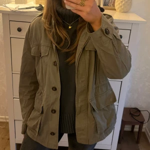 Olivgrön trenchcoat med knappar - Säljer en olivgrön trenchcoat med knappar och flera fickor framtill. Jättesnygg och perfekt nu till våren och sommaren!🤩🤩Passar M. SÄLJER ÄVEN FLER JÄTTEFINA PLAGG I MIN PROFIL 