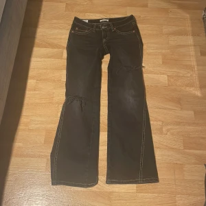 Super fina lågmidjade jeans! - Säljer ett par svarta lågmidjade bootcut jeans.  De har en snygg slitning på knäna och kontrasterande sömmar. Perfekta för en avslappnad stil. Sydde själv de lågmidjade! 