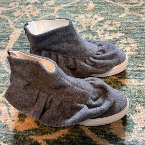 Grå sneakers med volangdetaljer -  Sneakers från Joshua Sanders med volangdetaljer och dragkedja bak. Storlek 38 och helt nya 