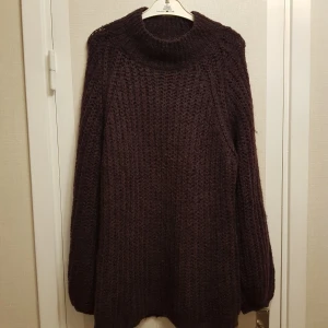 Mörklila ull tröja stlr M från Lindex - Säljer en mysig mörklila stickad tröja från Lindex. Tröjan har en hög krage och långa ballong ärmar, perfekt för kyliga dagar. Materialet består av akryl, polyamid och ull vilket gör den både varm och bekväm.