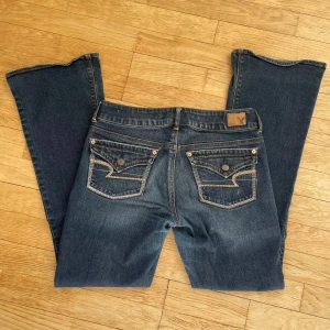 Low Waist jeans - Lågmidjade, bootcut jeans ännu från American Eagle med supersnygga fickor! Lite lite slitna vid längst ner i benen vid marken, men det är inget som stör! Annars superbra skick!! Pris kan diskuteras vid snabb affär, skriv för mått eller fler frågor🥰