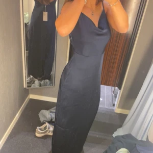 Mörkblå balklänning från VILA - Fin mörkblå balklänning från VILA med smala axelband och v-ringad både där bak och fram. Den är helt ny, aldrig använd och jag säljer den då jag inte hann lämna tillbaka i tid. 