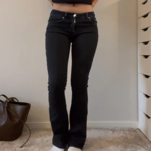 Lågmidjade byxor  - Svarta utsvängda lågmidjade byxor från Bikbok i storlek 32 knappt använda