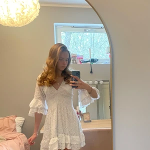 Vit klänning med volanger - Charmig vit klänning med v-ringning och volanger. Klänningen har trekvartsärmar och ett vackert broderat mönster. Perfekt för sommarens alla tillfällen. Klänningen är onesize🥰 Priset kan diskuteras💗 Skriv gärna om ni har några frågor❣️