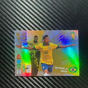 Fotbollskort Neymar Jr. Brasilien - Säljer ett glänsande fotbollskort från Panini med Neymar Jr. i Brasiliens landslagströja. Kortet är en del av Adrenalyn-serien och har en färgglad design med texten 'Top Master'. Perfekt för samlare av fotbollskort!