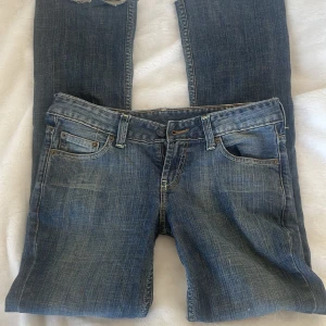 Blåa lågmidjade jeans från United Colors of Benetton - Snygga blå jeans från United Colors of Benetton med klassisk femficksdesign. De har en normal passform och är perfekta för en avslappnad stil. Jeansen har en lätt tvättad look och en bekväm midja. Jag har dock klippt dom där nere för dom va för långa annars är dom i väldigt bra skick