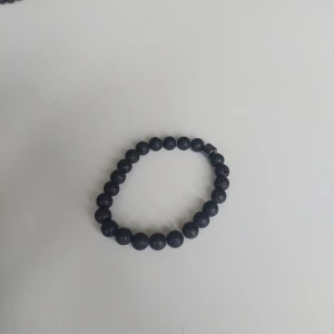 Svart pärlarmband med lavasten - Stilrent svart armband med runda pärlor av lavasten. Elastiskt band gör det enkelt att ta på och av. Perfekt accessoar för en cool och minimalistisk look.