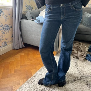 Mörkblå bootcut jeans - Snygga mörkblå jeans med bootcut passform och klassiska fickor fram och bak. Jeansen har normal midja och är tillverkade i ett mjukt denimtyg med lite stretch. Perfekta för dig som gillar en tidlös och avslappnad stil.