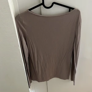 Beige långärmad topp - Säljer en enkel och stilren beige långärmad topp med rund halsringning. Perfekt att matcha med jeans eller kjol för en clean look. Materialet känns mjukt och följsamt.