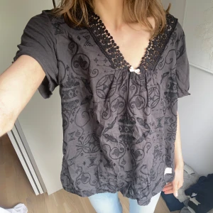 Svart blus från Odd Molly - Supersöt kortärmad blus med spetsdetaljer och en rosett🎀