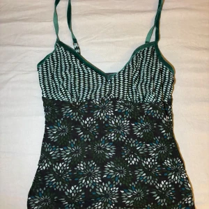 Mönstrad linnetopp från Mexx XS - Snygg linnetopp från Mexx i storlek XS med smala axelband. Toppen har ett coolt mönster med gröna, blå och vita blommor samt grafiskt mönster upptill. Materialet är mjukt och stretchigt, perfekt för varma dagar. Justerbara axelband för bästa passform.