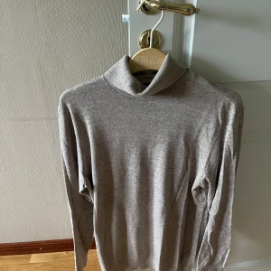 beige polotröja från HM - Snygg och enkel beige polotröja från HM med lång ärm och klassisk polokrage. Tröjan är i mjukt material och har en rak passform som funkar till många olika stilar. Perfekt för lager-på-lager under kyliga dagar.