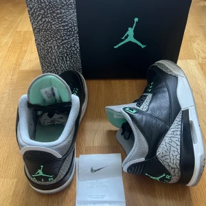 Nike Jordan 3 Green Glow - Säljer ett par Nike Air Jordans med svart skinn, grå detaljer och mintgröna accenter. Skorna har klassiskt elefantmönster vid tån och hälen, samt snörning och rund tå. Perfekta för dig som gillar streetwear och sneakers med unik design. Dem är såklart äkta kvitto finns på bilden dem har helt nya med box och allting ingen tecken på användning bara testade, säljer för att dem bara står och tar plats. Ny pris 2500. 
