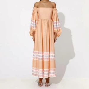 By malina Lou klänning  - Superfin långklänning i persikofärg med offshoulder och vida ärmar. Klänningen har broderade mönster i vitt, rosa och blått på ärmar och kjol. Perfekt för sommarens alla tillfällen!/storlek small/nyskick/nypris 4000:-