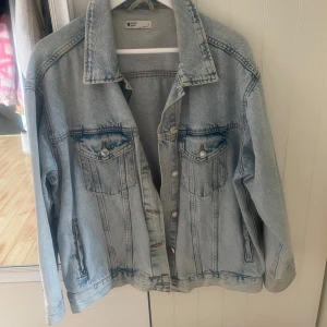 Ljusblå oversized jeansjacka - Snygg ljusblå jeansjacka från Gina Tricot med klassisk krage, bröstfickor med knappar och raka sömmar. Jackan har en oversized passform och är tillverkad i slitstarkt jeanstyg. Perfekt att slänga över en hoodie eller t-shirt för en chill look.