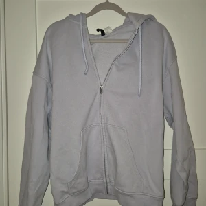 Ljuslila hoodie med dragkedja, S - Ljuslila hoodie i storlek S med dragkedja framtill och huva med snören. Tröjan har känguruficka och är långärmad.  Mjuk insida och klassisk passform.