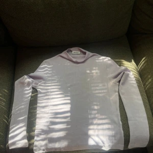 Ljuslila polotröja från Weekday - Säljer en tunn och ribbad ljuslila polotröja från Weekday. Tröjan har lång ärm och en hög krage som ger en clean och stilren look. Perfekt att styla lager på lager eller bära som den är. Materialet känns mjukt och följsamt mot huden. Små skador finns men går att fixa! 