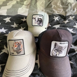 Tre kepsar med djurmotiv - Säljer tre kepsar med broderade djurmotiv: tiger, ko och silverräv. Kepsarna har klassisk form med böjd skärm och justerbar baksida. En är svart med nät, de andra två är ljusa. Perfekt accessoar för dig som gillar unika detaljer och djur. Hör av er vid frågor! Dessa kepsar är i bra skick.