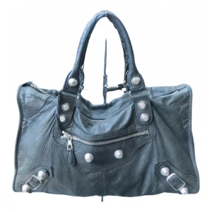 Svart Balenciaga City handväska i skinn - Ikonisk svart 100% äkta Balenciaga City handväska i mjukt skinn med silverfärgade nitar, dragkedja framtill och coola spänndetaljer. Väskan har dubbla handtag och klassisk slouchy form. Knappt använd. 