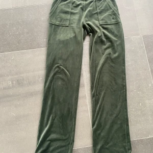 Mörkgröna mjukisbyxor med fickor - Säljer ett par mörkgröna mjukisbyxor med raka ben och stora fickor framtill. Byxorna har även dekorativa fickor med knappar bak. Perfekta för en avslappnad stil och riktigt sköna att ha på sig.