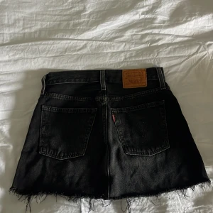 Svart lågmidjad jeanskjol från Levi's - Den är i modellen icon och man kan dra ner den och klippa efter behov☺️Nypris ca 700