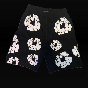 Denim tears shorts - Denim Tears Shorts A powerful blend of culture and craftsmanship. Denim Tears shorts feature premium denim construction, elevated with bold embroidery and meaningful motifs that speak to Black identity and heritage. Whether it’s the iconic cotton wreath or expressive graphic details, each pair makes a statement beyond style.