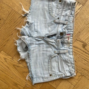  Lågmidjade jeansshorts från Levi's - Säljer ett par ljusblå jeansshorts från Levi's med råa fransade kanter och klassiska fem fickor. Shortsen har låg midja och är ganska korta💗.
