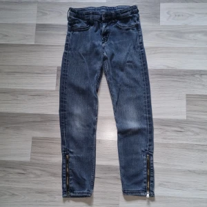 Blå vintage skinny jeans med dragkedjor H&M - Snygga blå vintage skinny jeans från H&M med dragkedjor vid bensluten. Jeansen har klassisk femficksdesign, normal midja och är tillverkade i stretchig denim för en tight passform. Perfekta för dig som gillar en stilren look med lite edge.