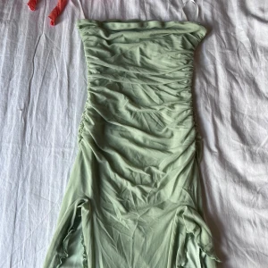 Ljusgrön långklänning med volang - Supersöt ljusgrön långklänning från shein med smala axelband och rynkade detaljer över hela klänningen. Klänningen har volangkant nertill och slitsar med vågiga kanter som ger en flowy känsla. Perfekt för dig som vill sticka ut med en unik look.