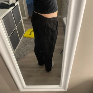 Svarta linnebyxor med snörning - Säljer ett par svarta linnebyxor med avslappnad passform och dragsko i midjan. Byxorna har raka ben och resår i midjan för extra komfort. Perfekta för en chill och stilren look.