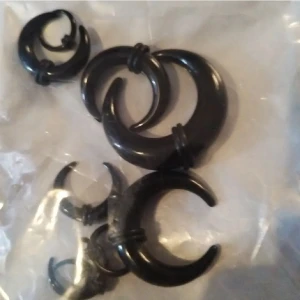 Svarta crescent stretchpercing kit i plast - Coola svarta crescentformade örhängen/septum i plast. Säljs i flera storlekar, perfekta för dig som gillar alternativ stil och vill sticka ut. Snygg och edgy design med tribalvibbar.