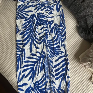 Vit och blå långkjol med bladprint - Snygg långkjol i vitt med blått bladliknande mönster. Kjolen har en slits