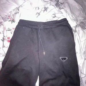 Svarta mjukis shorts från Prada - Svarta mjukisshorts från Prada med klassisk dragsko i midjan och diskret Prada-logga på benet. Byxorna har en relaxed fit och är tillverkade i mjukt bomullsmaterial, perfekta för en chill och stilren look.
